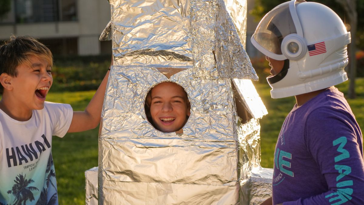 Kids playing with a homemade cardboard and foil rocket