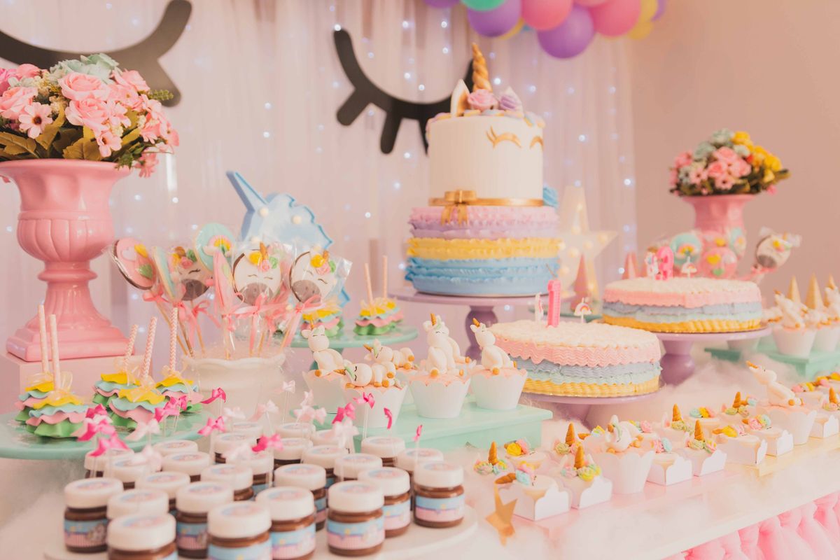 Pastel unicorn-themed dessert table with cakes and cupcakes